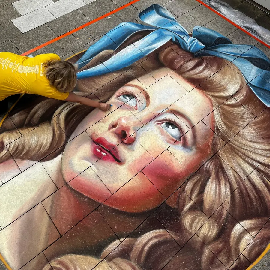 Close street chalk portrait of a woman gazing upward with a blue bow in her curls