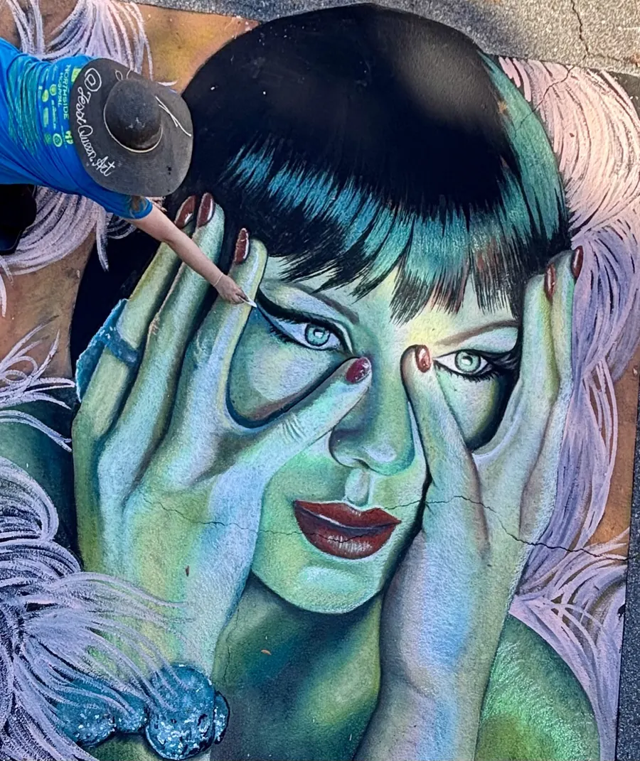 Jessi drawing a green-toned chalk portrait of a woman covering her face with her hands