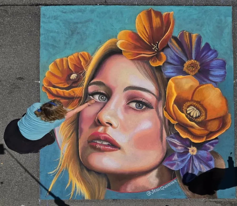 Jessi blending a chalk portrait of a blonde woman surrounded by orange and purple flowers
