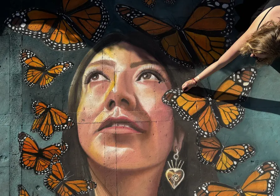 Jessi drawing a chalk portrait of a woman surrounded by monarch butterflies
