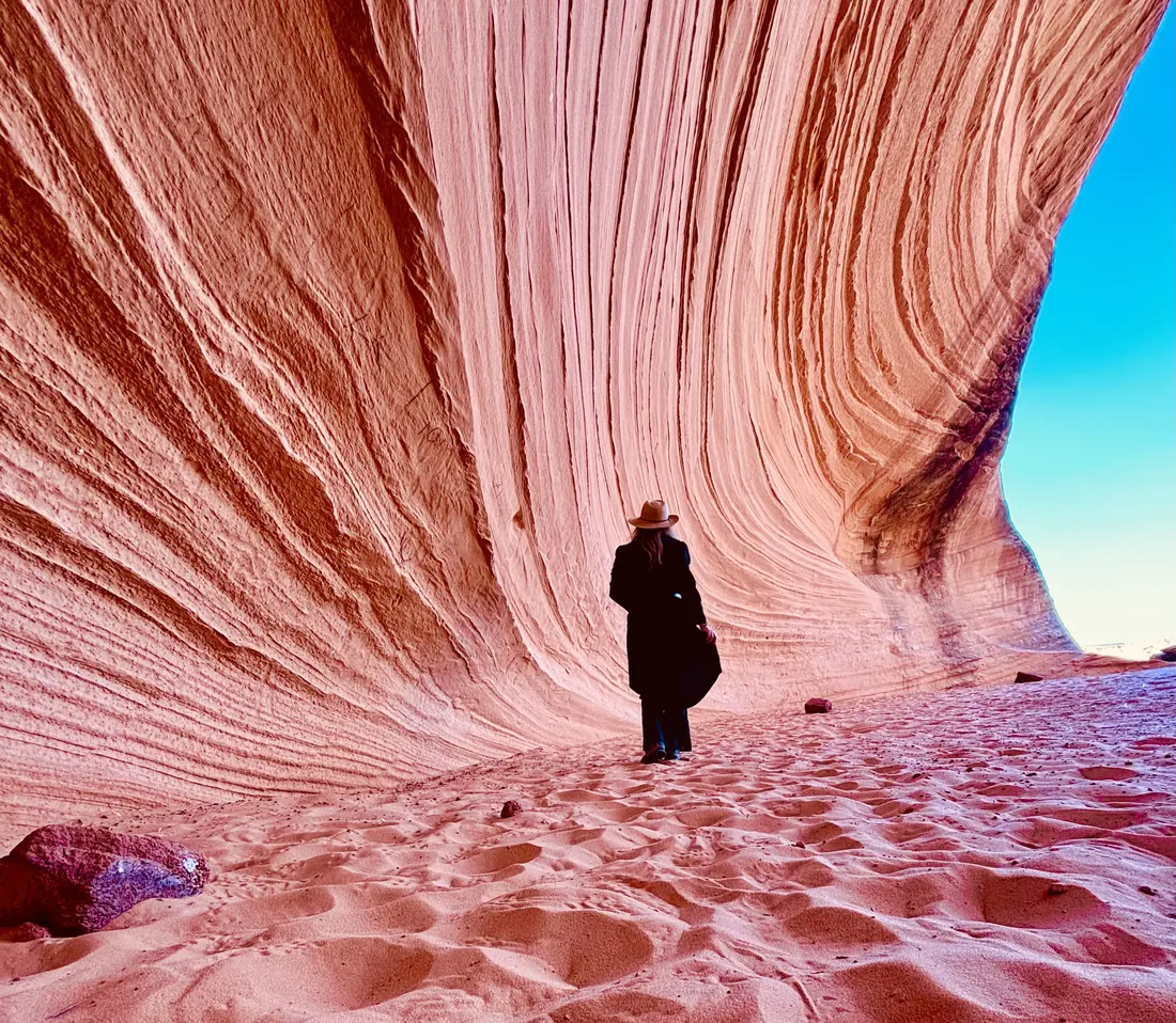 Jessi standing small among the swirling pink sandstone walls of a desert canyon