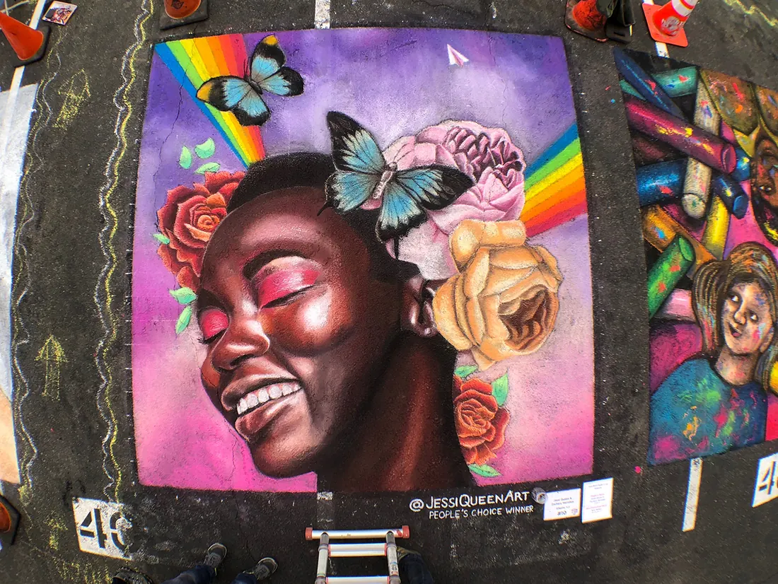 Chalk portrait of a laughing woman crowned with roses and butterflies under a rainbow, Tempe 2019
