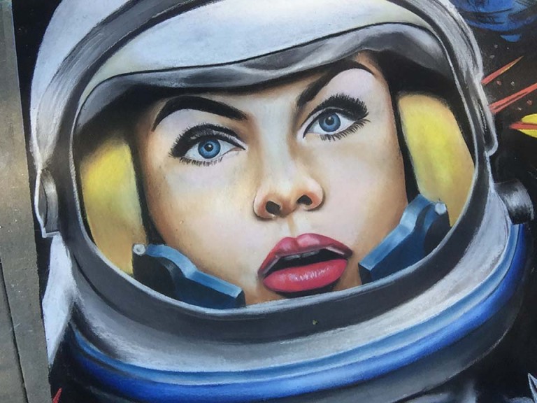 Chalk portrait of a blue-eyed woman with red lips inside an astronaut helmet