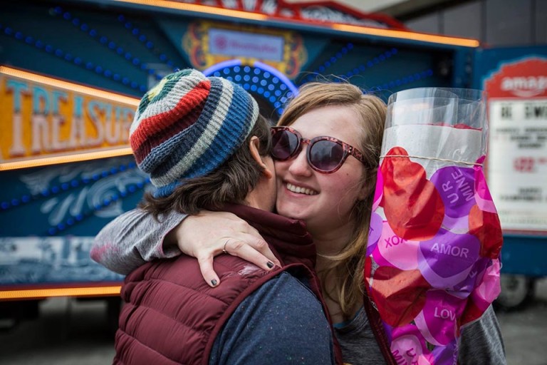 Two friends hugging, one holding a heart-print bag, at the Amazon Treasure Truck Valentine’s event