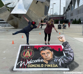 Two people balancing above a 3D chalk welcome mural for Atlanta United coach Gonzalo Pineda