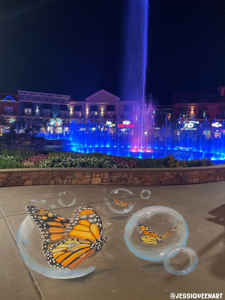 3D chalk monarch butterflies on bubbles at night, with a lit fountain glowing blue behind