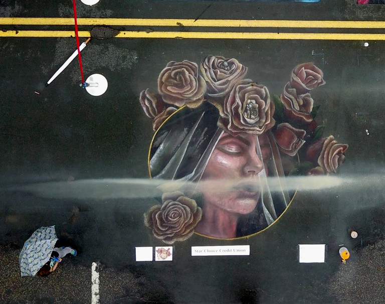 The veiled lady chalk portrait from above on a dark street, half washed away by rain