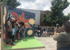 Family posing in the Decatur Arts Festival backdrop while a friend takes their photo