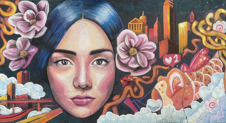 Chalk portrait of a woman with blue hair surrounded by magnolias, a city skyline and swirling ribbons