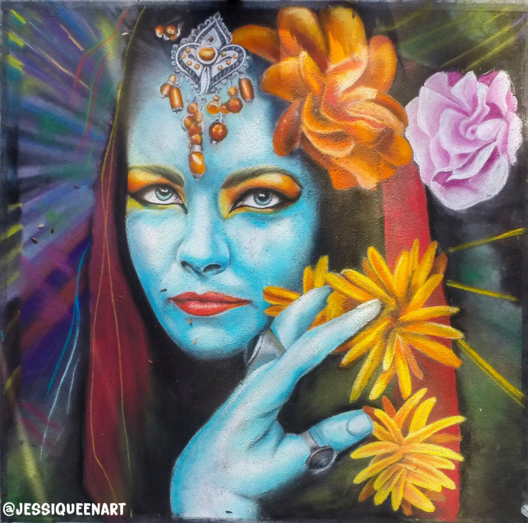 Chalk portrait of a blue-skinned woman with a jeweled forehead piece and orange and yellow flowers