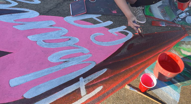 Close-up of white Albany script being chalked over a pink heart