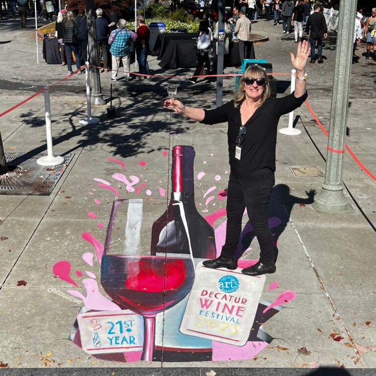 Woman toasting atop a 3D chalk wine glass and bottle for the 21st Decatur Wine Festival