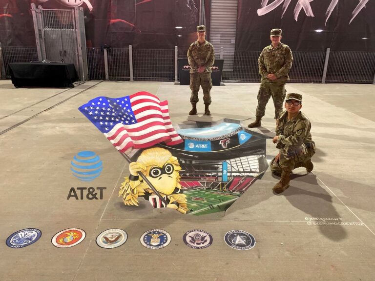 Three soldiers posing with a 3D chalk drawing of the Atlanta Falcons mascot waving an American flag out of the stadium, above the seals of the U.S. military branches