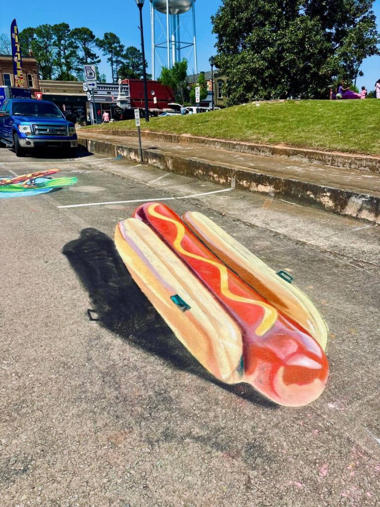 3D chalk hot dog with a mustard zigzag that appears to rise off the pavement