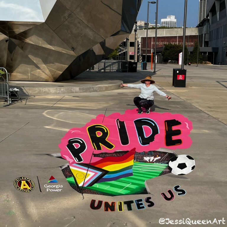 Jessi crouching behind a 3D chalk Pride Unites Us mural with a progress flag, soccer ball and stadium field