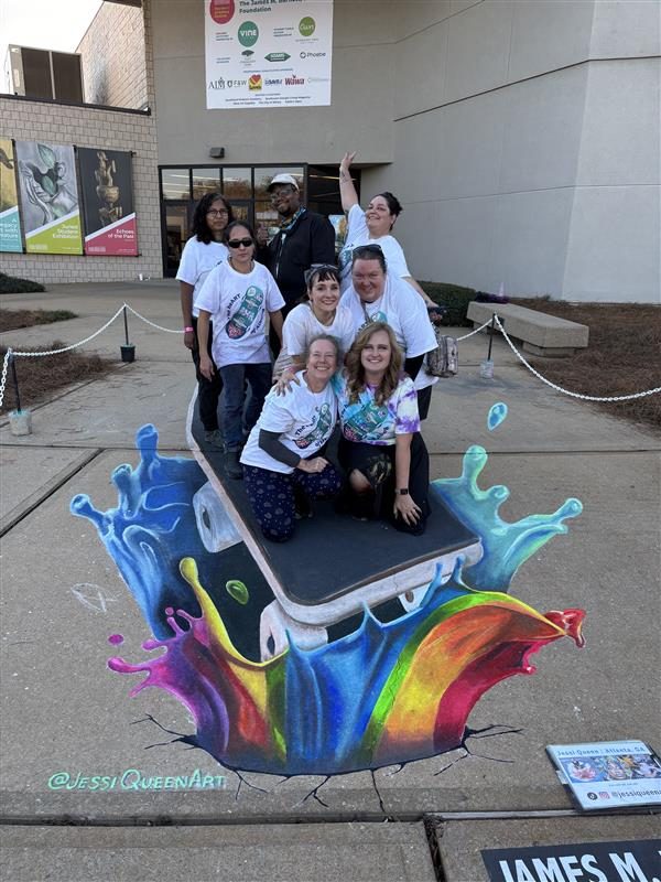 Group in matching shirts posing on a 3D chalk phone bursting from a rainbow paint splash