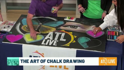 Still from the ATL Live segment: the hosts and artists shading pink, yellow and teal chalk hearts around the ATL Live drawing