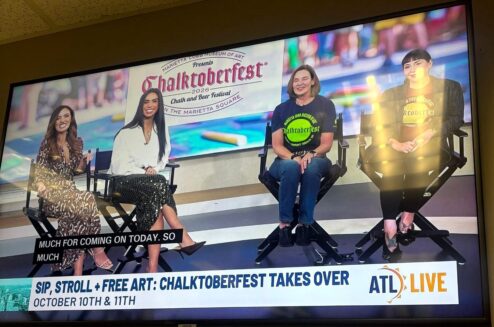 TV screen showing the ATL Live hosts with two Chalktoberfest guests, captioned Sip, Stroll + Free Art: Chalktoberfest Takes Over, October 10th and 11th