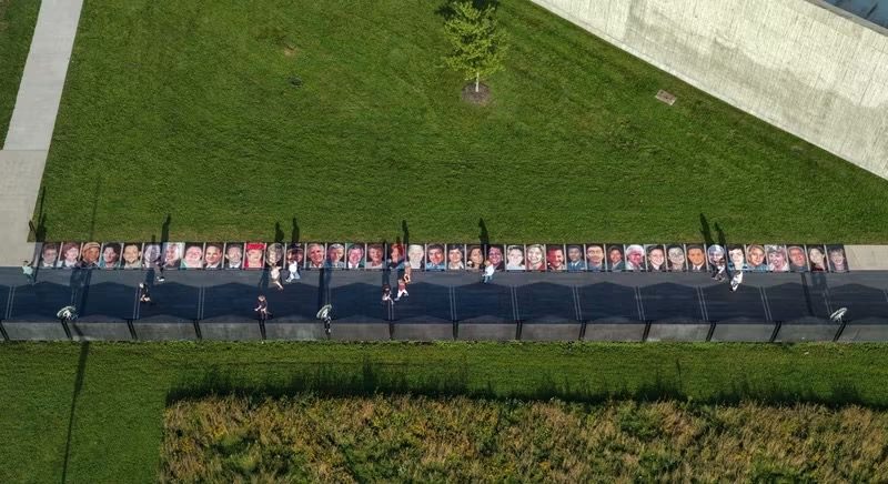 Aerial photo of all 40 chalk portraits of the Flight 93 passengers and crew in a long line along the memorial walkway, with visitors walking beside them
