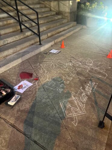 The chalk drawing in its outline stage on a Marietta sidewalk at dawn: flowers around the FOX 5 Atlanta and City of Marietta logos, with chalk supplies nearby