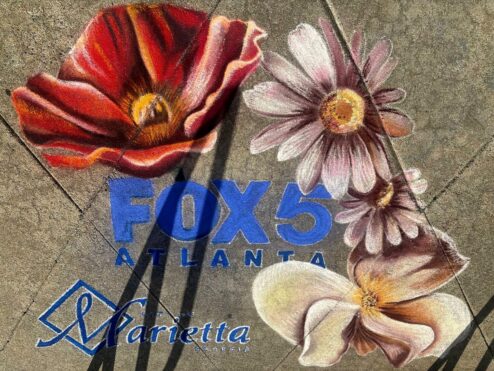 Close view of the chalk poppy, daisies and magnolia framing the FOX 5 Atlanta and City of Marietta logos