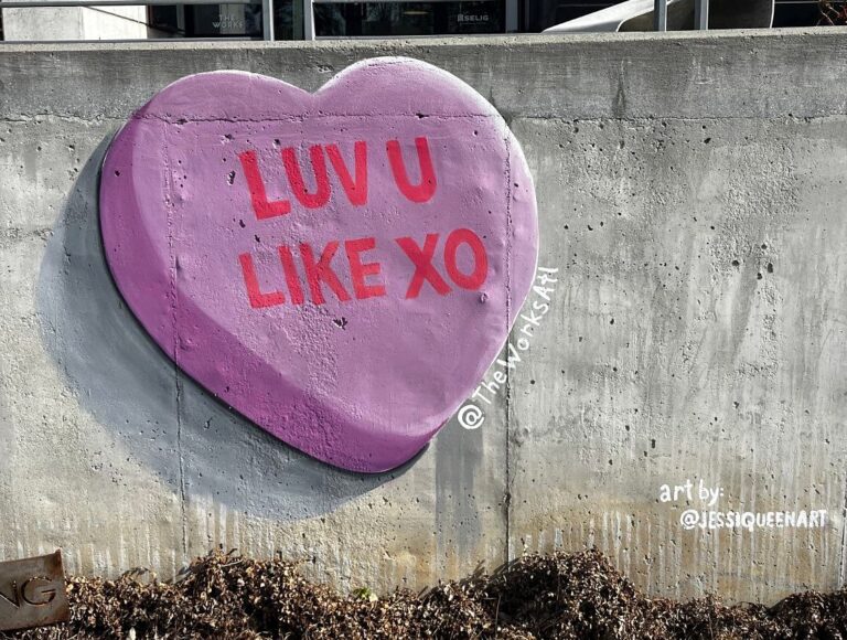 Painted 3D lavender candy heart reading Luv U Like XO on a concrete wall