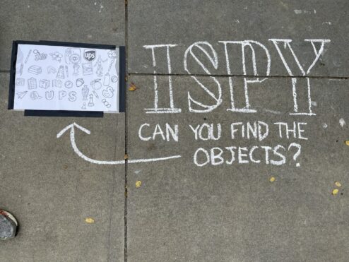 Hand-chalked sign reading I Spy, can you find the objects, with an arrow pointing to a printed key of objects hidden in the drawing