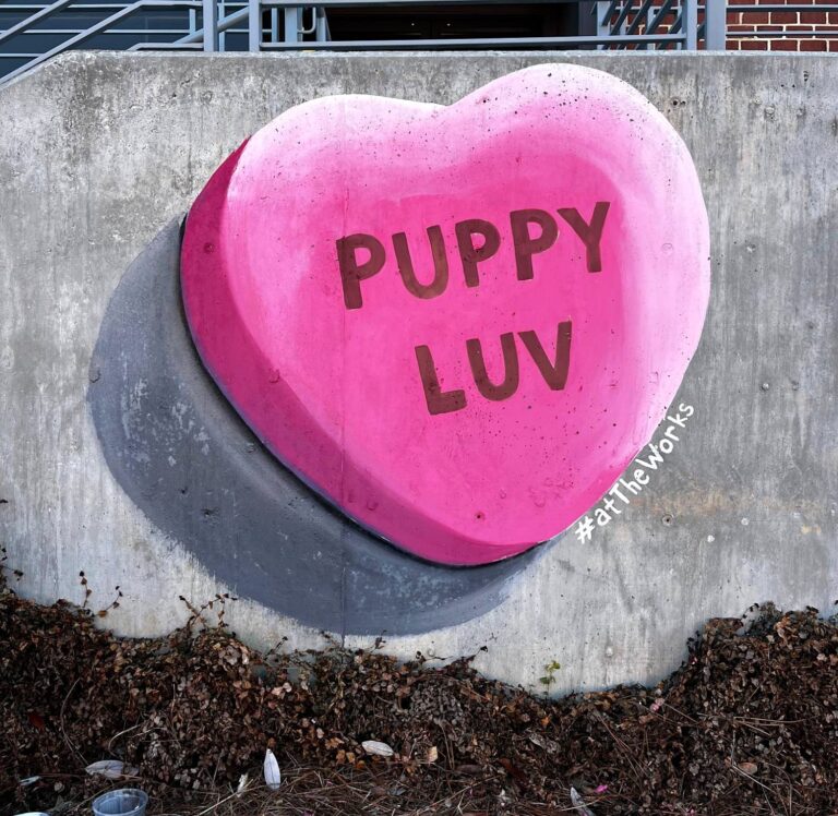 Painted 3D pink candy heart reading Puppy Luv on a concrete wall at The Works