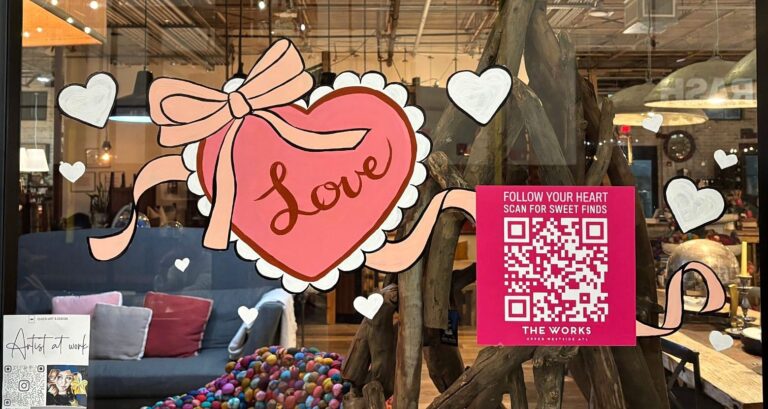 Valentine's window painting of a pink lace heart reading Love, tied with a peach ribbon bow