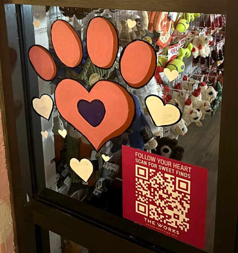 Valentine's window painting of a coral paw print with a heart-shaped pad on a pet shop door
